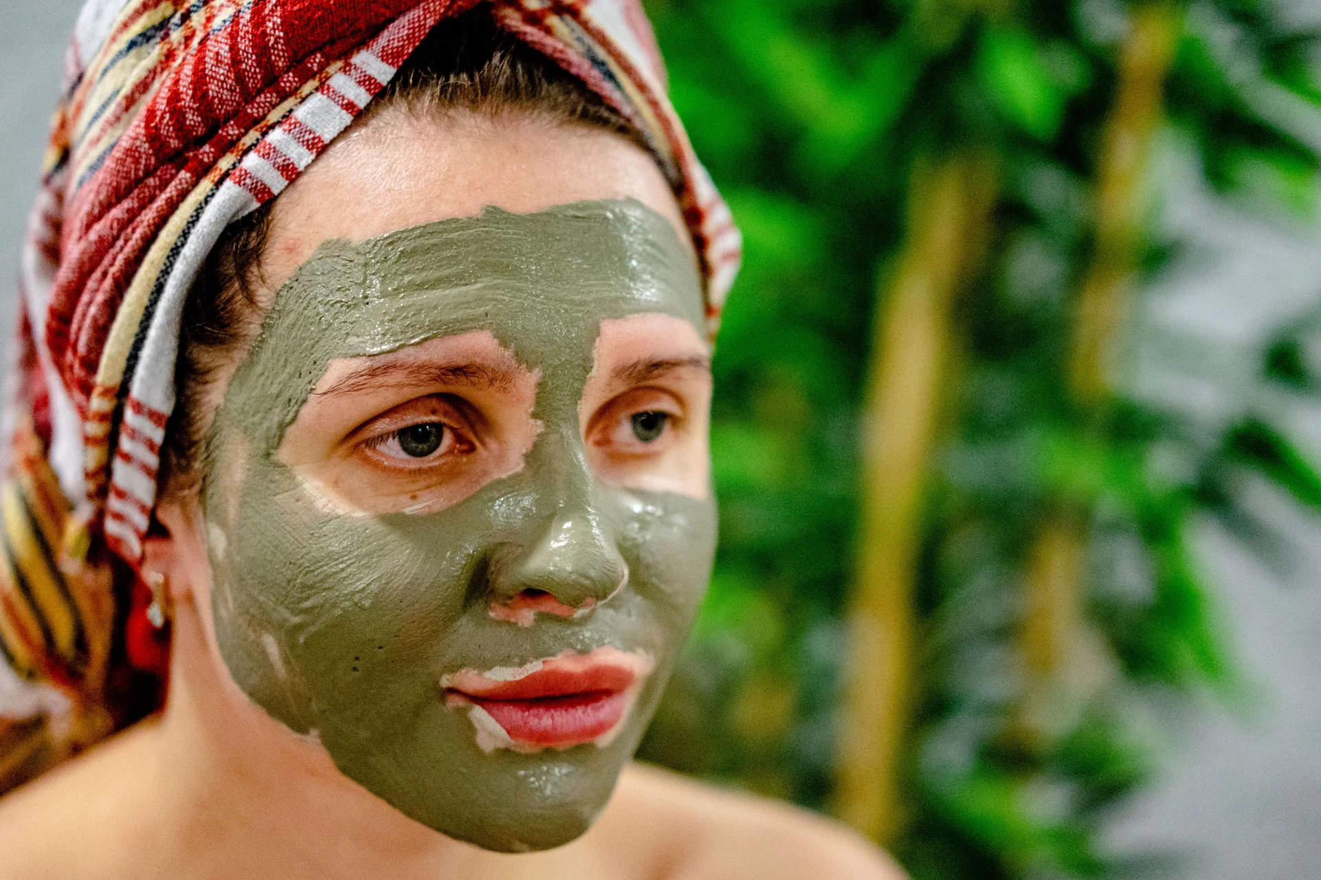 Kobieta z zamkniętymi oczami relaksuje się podczas zabiegu z maseczką błotną w spa.